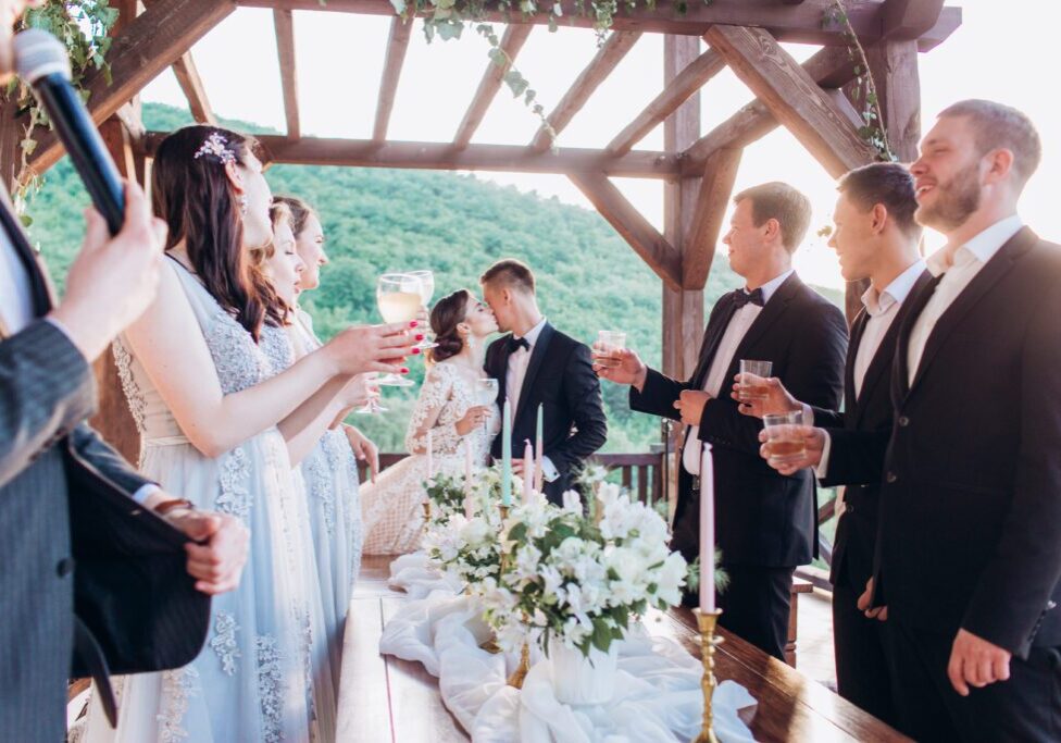 Boho style wedding party. Banquet with friends, bride and groom outdoors.